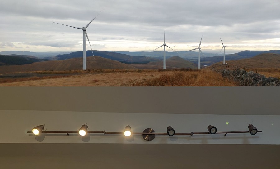 Wind turbines on a Scottish hillside above a kitchen light bar with several failed bulbs